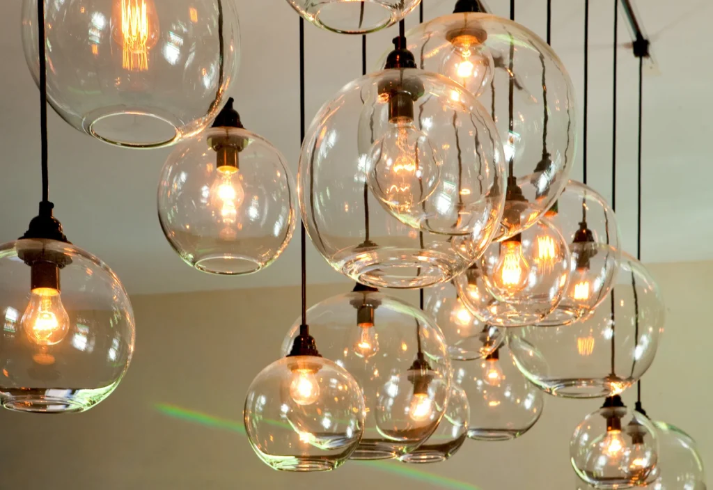 Cluster of clear glass globe pendant lights glowing warmly, suspended from black cords.