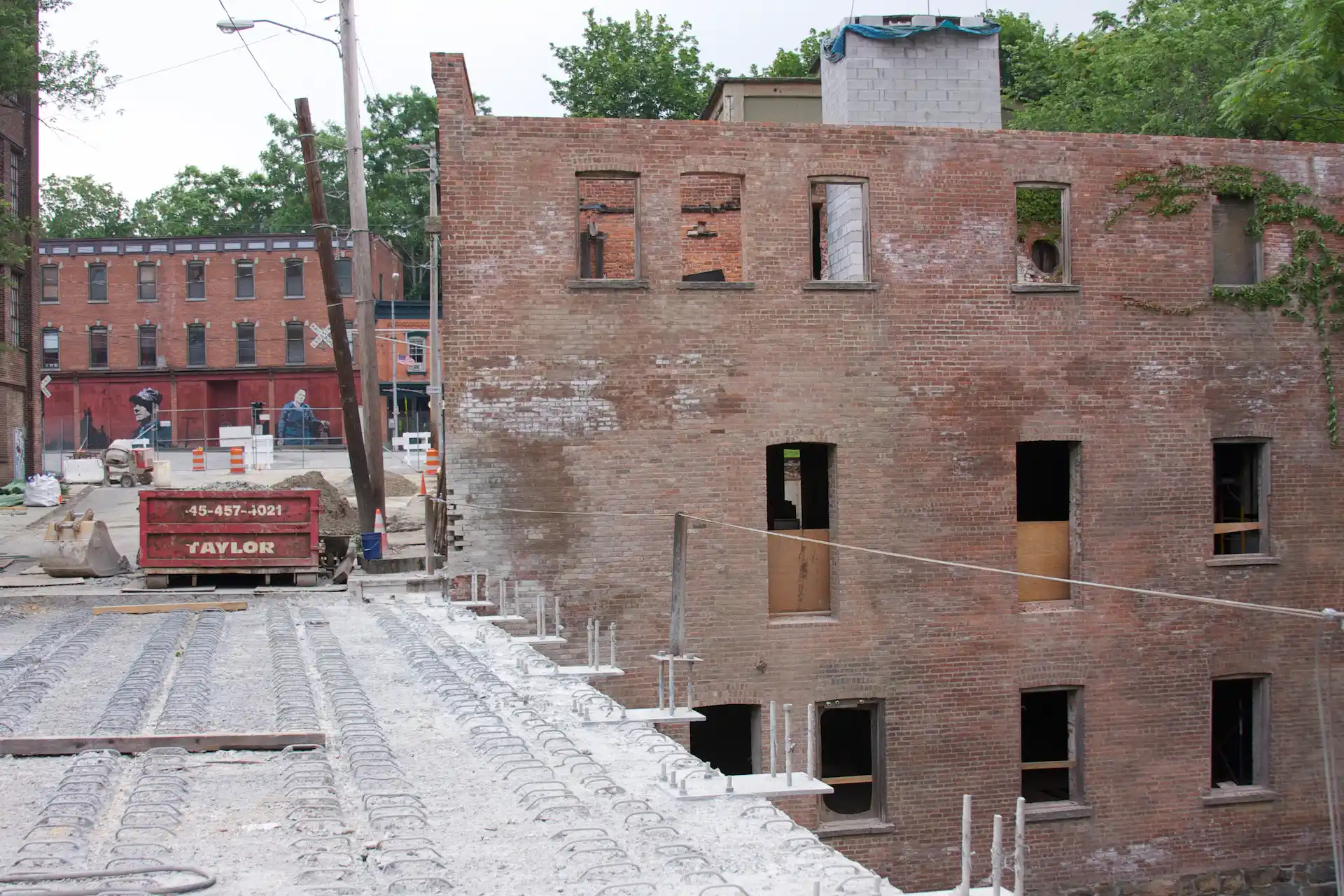 Brick building under renovation with exposed windows, construction materials, and equipment on a raised concrete surface.