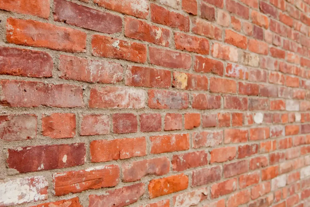 Close-up of a weathered red brick wall with visible mortar lines and varied brick textures.