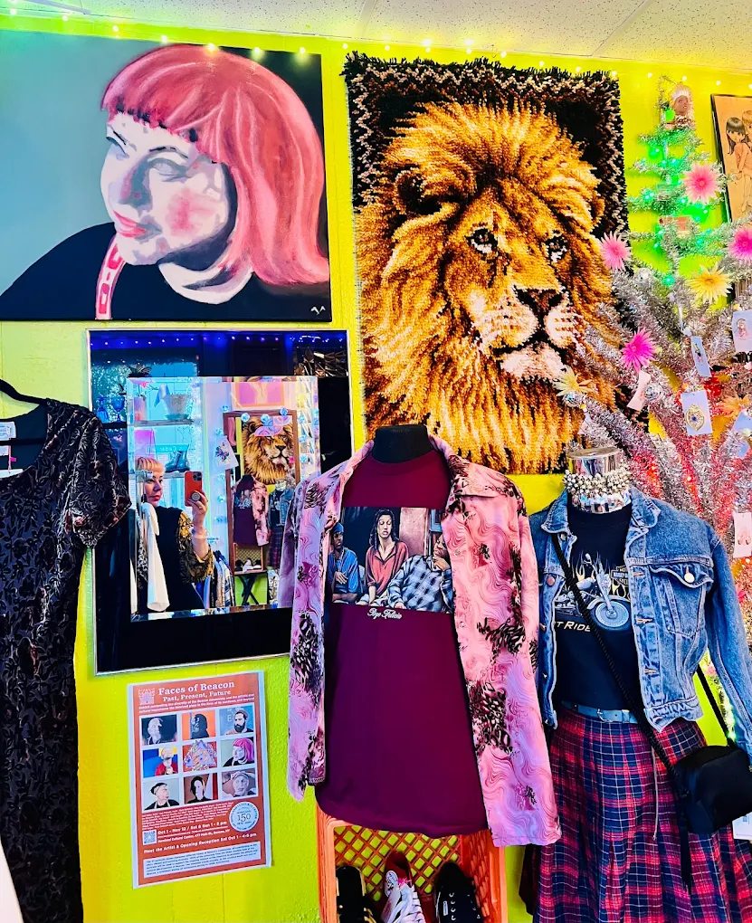 Colorful boutique interior with art portraits, lion tapestry, mannequins, and festive decor.