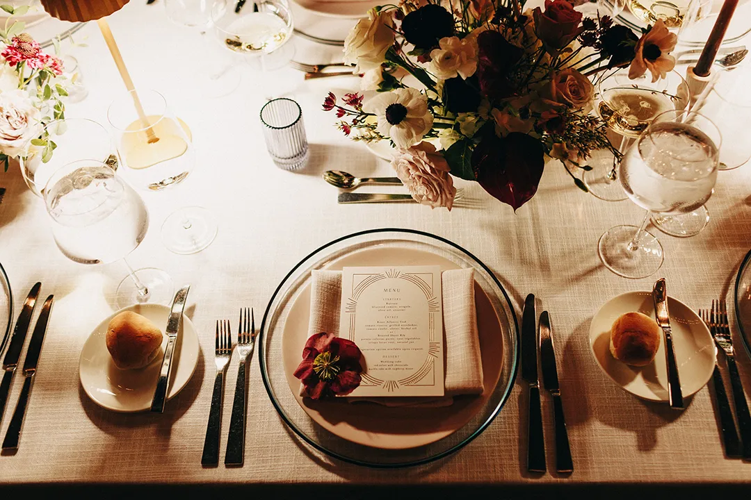 Elegant wedding table setting with menu card, flowers, candles, and place settings.