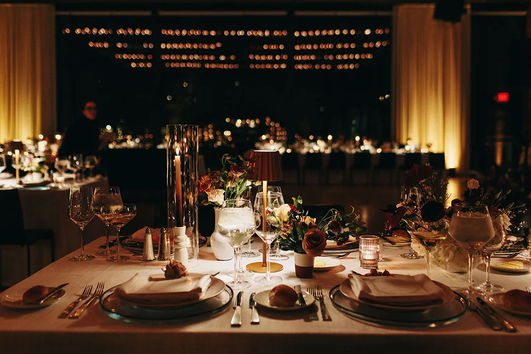 Candlelit wedding reception table with elegant place settings and floral centerpieces.