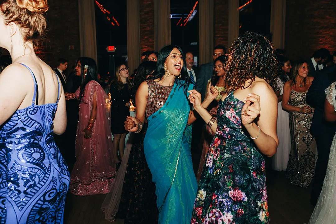 Guests dance joyfully in colorful formal attire at a wedding reception.