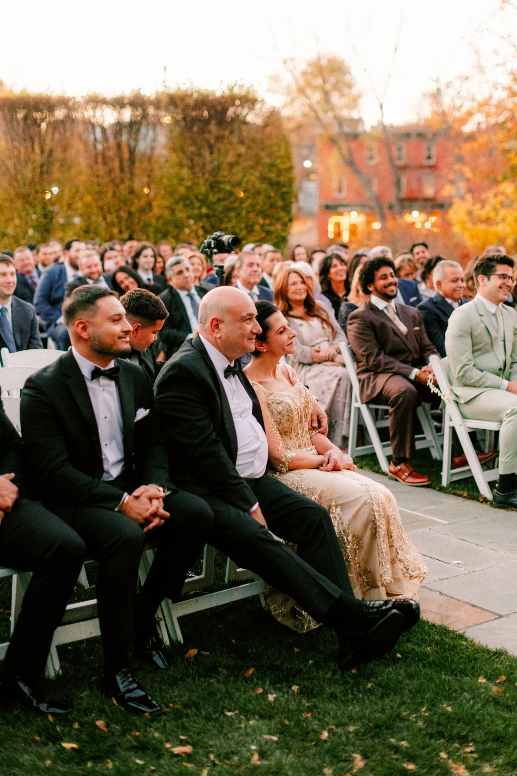 Guests seated at an outdoor wedding ceremony, smiling as they watch the vows.