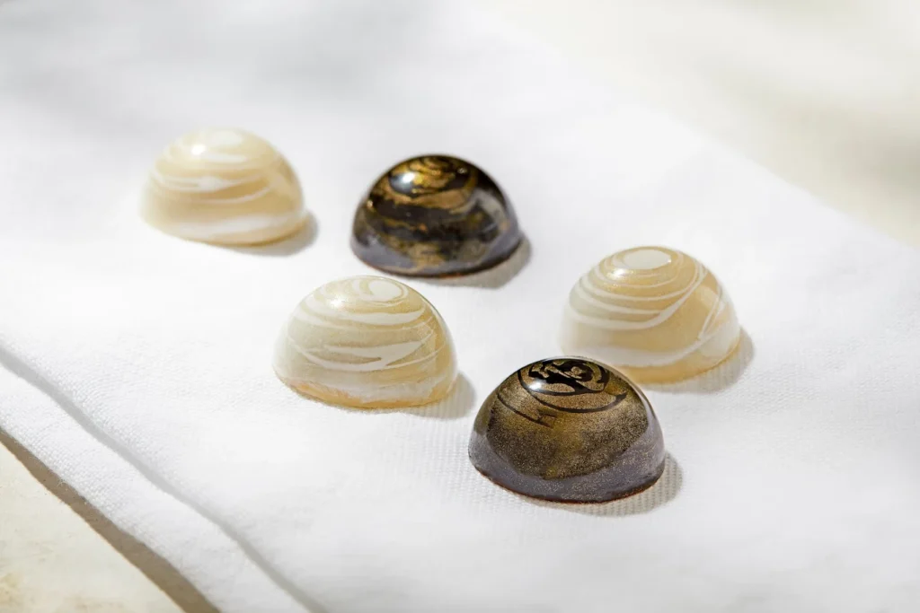 Assorted artisan chocolates with marbled designs on a white cloth.