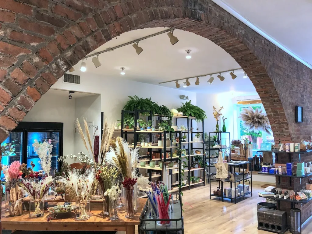 Brick-arched plant shop interior with shelves of greenery, dried flowers, and gifts.