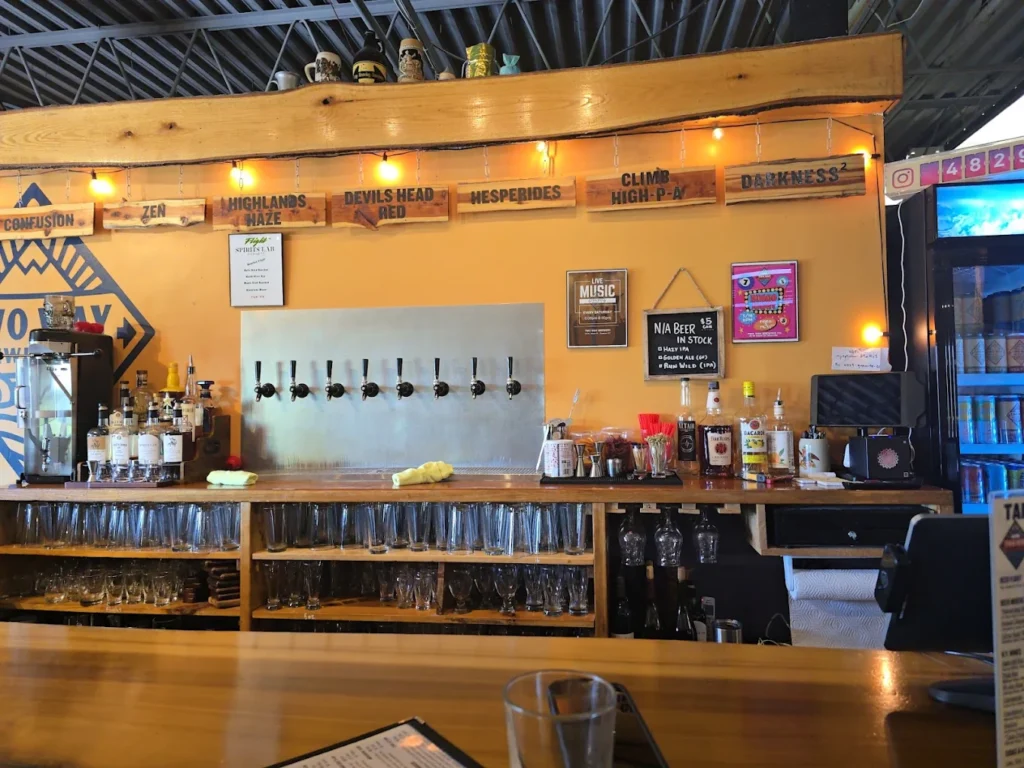 Craft brewery bar with beer taps, bottles, glassware, and wooden signage.