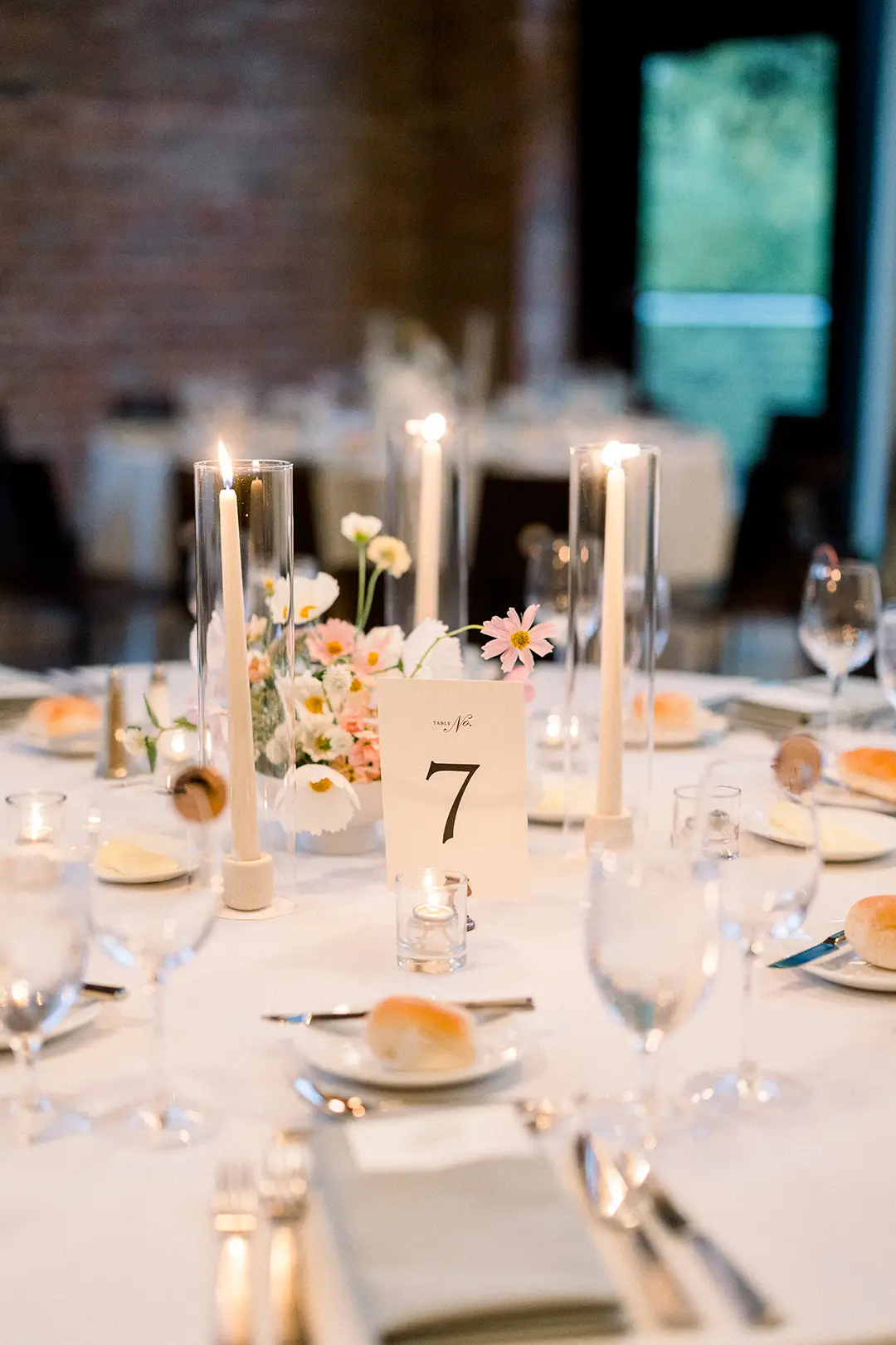 Wedding reception table with candles, floral centerpiece, and table number seven card.