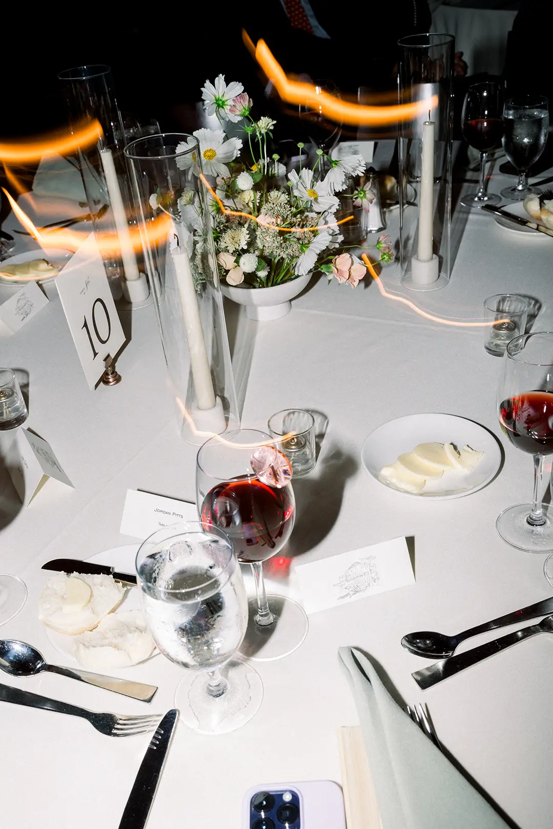 Wedding table setting with flowers, candles, wine glasses, and place cards.