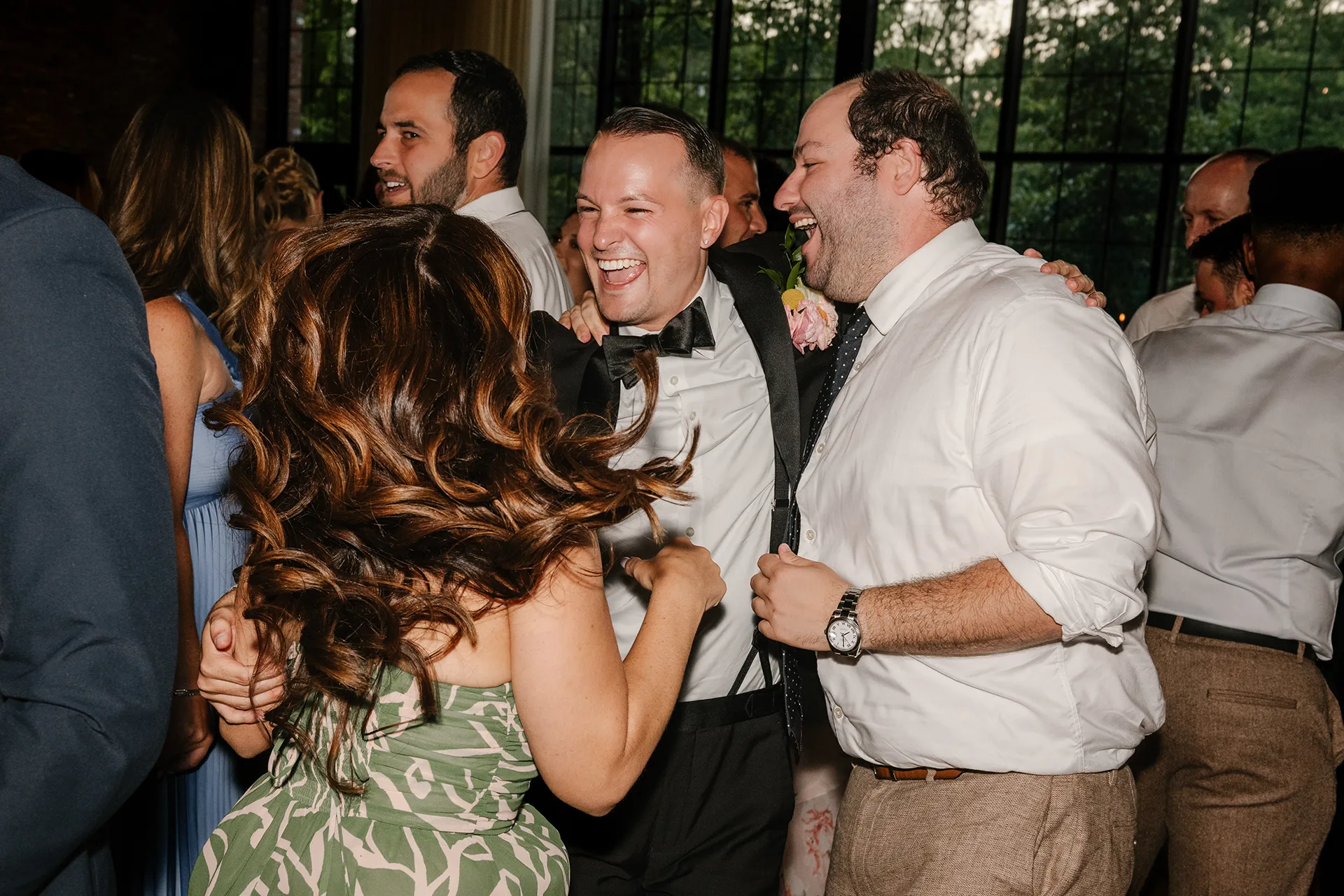 Guests laughing and dancing together at a lively wedding reception.