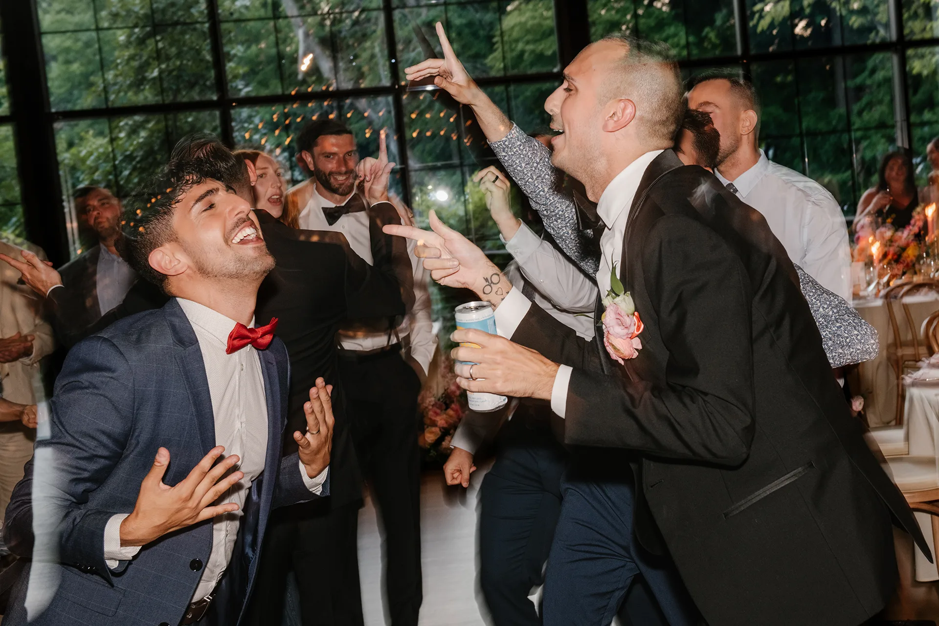 Guests dancing and cheering at a lively wedding reception indoors.