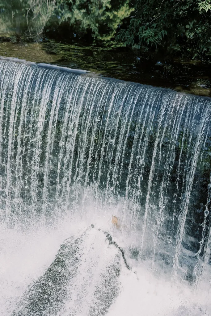 Close-up of water cascading over a small waterfall into a foaming pool below.