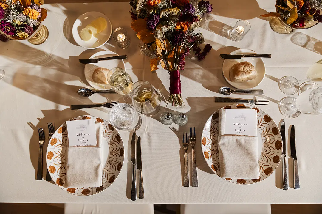 Overhead view of elegant wedding table settings with floral centerpieces, place cards, and glassware.