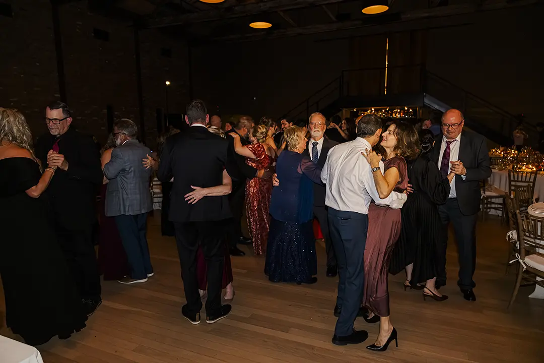 Guests dancing together on a dimly lit dance floor at a formal evening celebration.